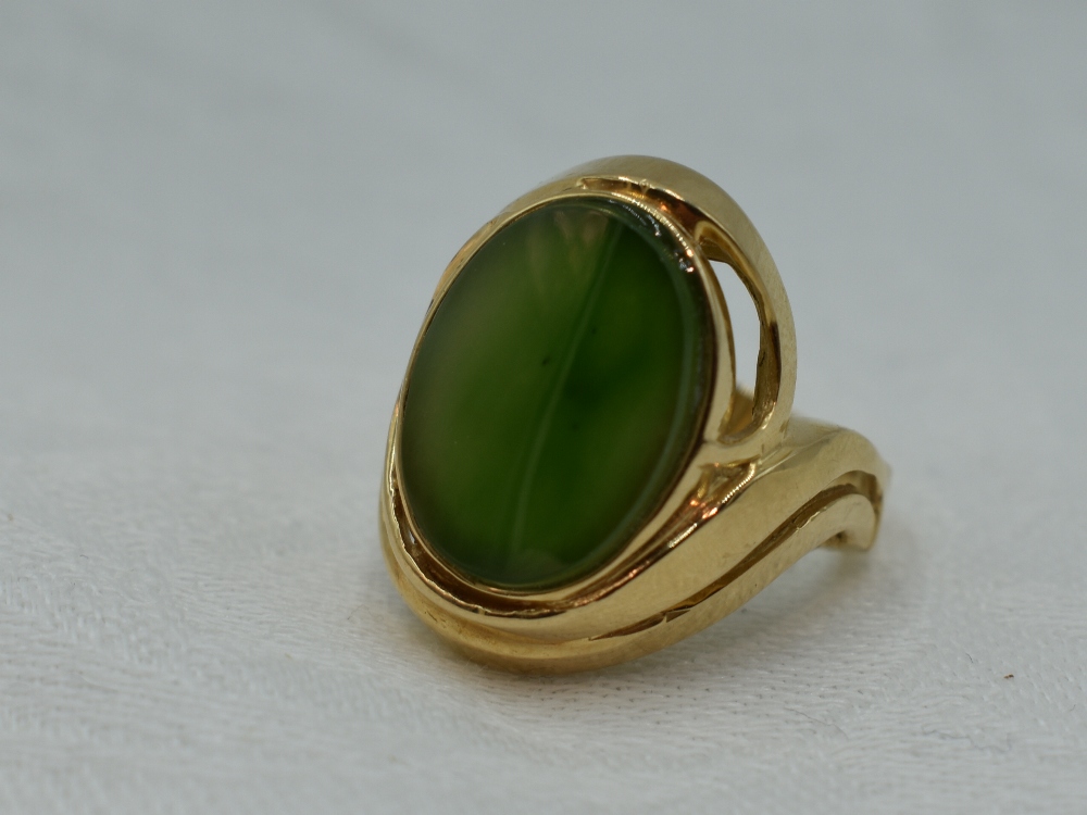 A lady's dress ring having a Canadian jade oval panel in a stepped collared mount on a yellow