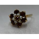 A lady's dress ring having a large garnet and seed pearl daisy cluster on a 9ct gold loop, size