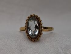 A lady's dress ring having an oval aqua marine style stone in a collared mount with twist decoration