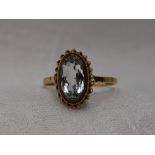 A lady's dress ring having an oval aqua marine style stone in a collared mount with twist decoration