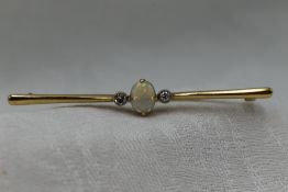 A 9ct gold bar brooch having a central opal flanked by two diamonds