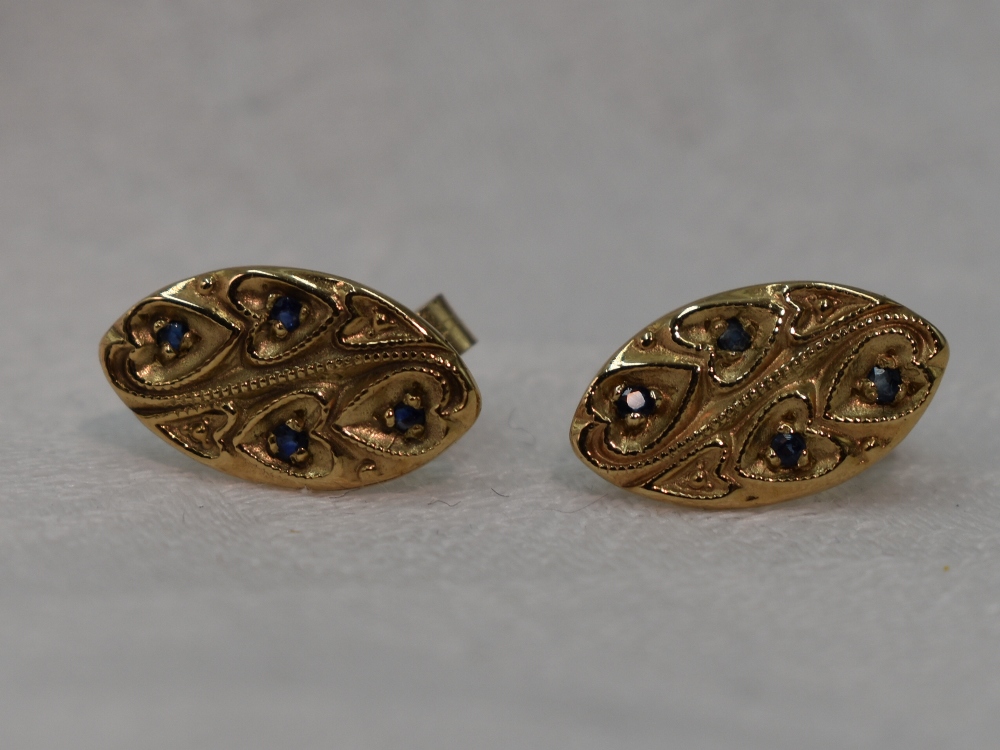 A pair of yellow metal stud earrings of lozenge form having sapphire chip decoration in heart and