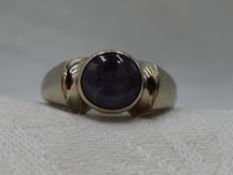 A lady's dress ring of Artisan form having a star sapphire cabochon in a collared mount to shaped