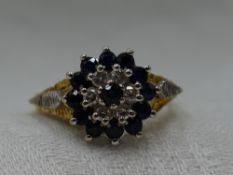 A lady's dress ring having a sapphire and diamond triple cluster to open raised shoulders on an 18ct