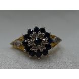 A lady's dress ring having a sapphire and diamond triple cluster to open raised shoulders on an 18ct