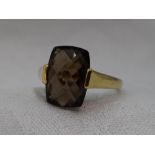 A lady's dress ring having a smoky quartz facetted panel in a tension mount on a 9ct gold loop, size