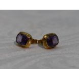 A pair of amethyst stud earrings having yellow metal collared mounts, no marks tested as 9ct gold