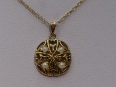 A 9ct gold pendant of pierced circular form having seed pearl decoration on a 9ct gold chain, approx