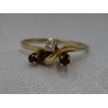 A lady's dress ring having a trio of diamond and rubies in a stylised mount on an 18ct gold loop,