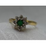 A lady's dress ring having an emerald and diamond cluster in a claw set mount on an 18ct gold