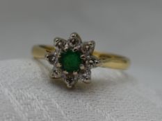 A lady's dress ring having an emerald and diamond cluster in a claw set mount on an 18ct gold