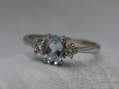 A lady's dress ring having a central aqua marine flanked by two diamonds in a claw set collared