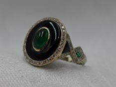 A lady's dress ring having a central emerald cabouchon in a black onyx oval mount with diamond