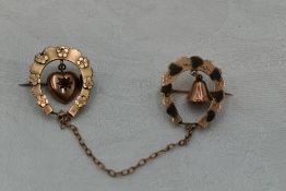 A Victorian 9ct gold horse shoe brooch duo with suspended heart and bell charms and chain connecter