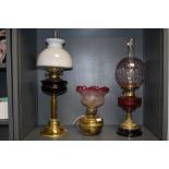 Two large antique oil lamps having decorative red glass detailing, also another which has been