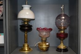 Two large antique oil lamps having decorative red glass detailing, also another which has been