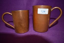 A pair of vintage copper mugs, one small and the other larger.