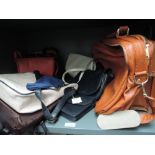 A collection of handbags, a lot leather and some still having tags attached also a vintage tan