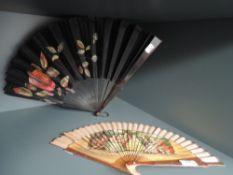 Two vintage fans, one with hand painted floral designs on black fabric, the other having classical