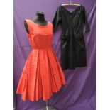 Two 1950s dresses, one tailored in textured black cotton, having large feature pockets and 3/4