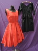 Two 1950s dresses, one tailored in textured black cotton, having large feature pockets and 3/4