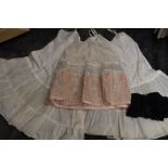 Three vintage petticoats, one of which has a flocked rose pattern to the scalloped hem, also