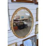 An oval bevelled glass mirror having gilt effect frame.