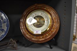 An aneroid barometer of button design with carved mahogany frame having enamel face dial
