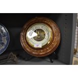 An aneroid barometer of button design with carved mahogany frame having enamel face dial