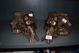 A pair of wall brackets with angel of cherub style design