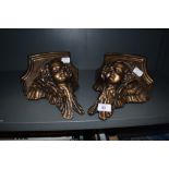 A pair of wall brackets with angel of cherub style design