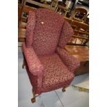 A reproduction wing back armchair , on cabriole legs with ball and claw feet