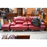 A pair of vintage style red leather armchairs and matching footstool, on chrome legs