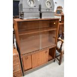 A vintage Ladderax style teak bookcase, having glazed upper section over double sliding door