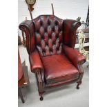 A traditional burgundy leather wing back armchair