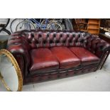 A traditional burgundy leather chesterfield settee