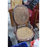 An early 20th Century stained frame salon chair having bergere canework seat and back