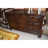 A dark stained Ercol sideboard, having central section of two short over three long drawers, flanked