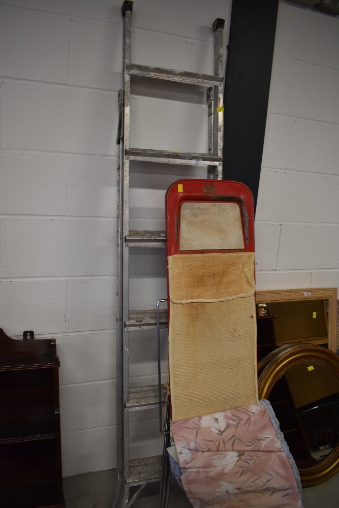 A vintage ironing board and set of aluminium ladders