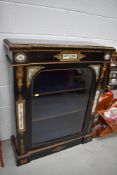 A 19th Century Empire style ebonised glazed pier cabinet having gilt metal and enamel decoration,