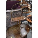 An antique oak and brass paper rack, having triple splay brass legs