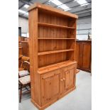 A traditional pine dresser with open shelves over double cupboard base, approx. dimensions width