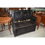 A 19th Century dark stained monks bench, having illustrative tavern panel decoration and dog of fo