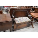 An early 20th Century oak monks bench having lion arms, on shepherds casters, width approx. 106cm