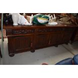 A traditional oak long sideboard, having carved frieze drawers and linen fold cupboards, width