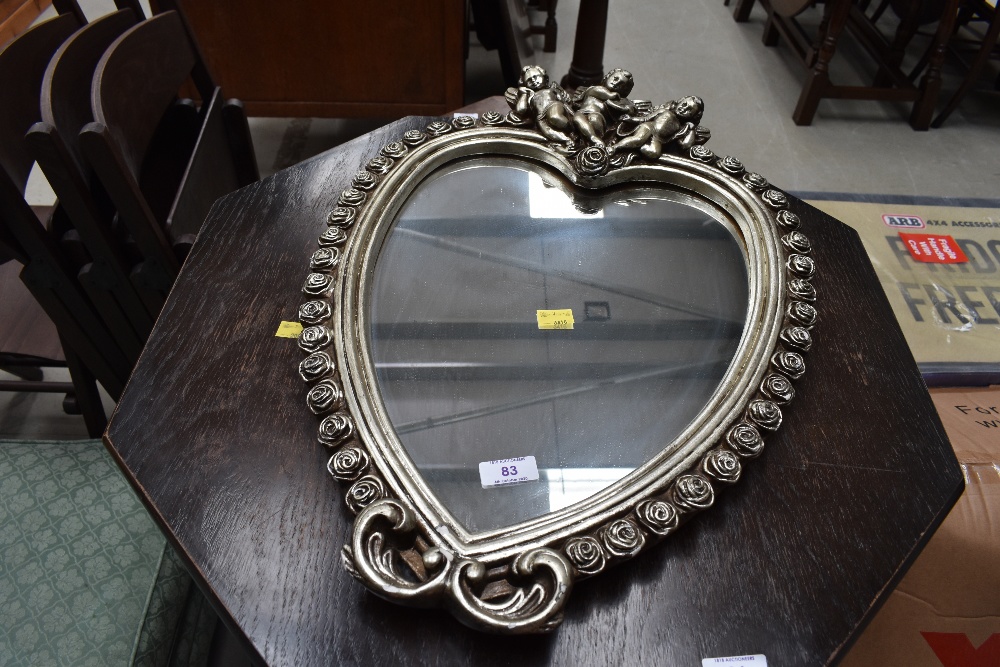 A reproduction mirror, heart shaped with cherub decoration, width approx. 40cm