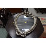 A reproduction mirror, heart shaped with cherub decoration, width approx. 40cm