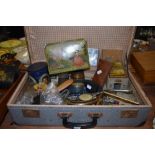 A suitcase containing an assortment of vintage items including a work box, enamel lidded jars, brass