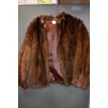 A short vintage fur jacket having leather inserts to back of arms, fully lined and in soft and