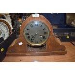 An ornate oak framed mantle clock having glass window and visible mechanism with chime